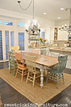 a dining room table with chairs and a chandelier in the middle of it