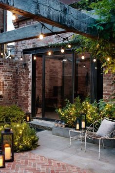 an outdoor kitchen bar area with brick walls and lights on the outside, surrounded by greenery