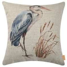 a blue heron sitting on top of a pillow next to some tall grass and reeds