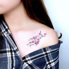 a woman with a flower tattoo on her shoulder and chest is looking at the camera