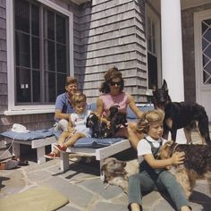 a family sitting on the porch with their dogs