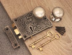 an assortment of antique keys and knobs on a wooden table with metal door handles