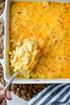 a person holding a spoon in a casserole dish with cheese and meat on it