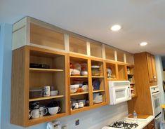 a kitchen filled with lots of wooden cabinets and white counter top space next to a microwave oven