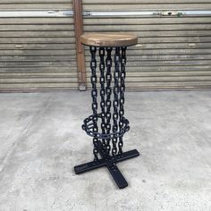 a table made out of chains sitting on top of a cement floor next to a garage door