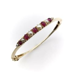 This is part of Chairish’s Fine Jewelry assortment.  The centrepiece of this charming bracelet was most likely once a brooch, converted at some point into a stylish bangle. It contains six round half pearls and five oval-shaped cabochon rubies, prong-set into an alternating pattern, that has been beautifully incorporated into a knife edge bracelet. Each end of the bar culminates in triangular points, which marry into the knife edge for a clean and sophisticated look. The 14k gold bangle has a sa Ruby And Pearl, Charming Bracelet, Gold Bangle, Gold Bangles, Pearl Bracelet, Prong Setting, Ruby, Fine Jewelry, Bangles