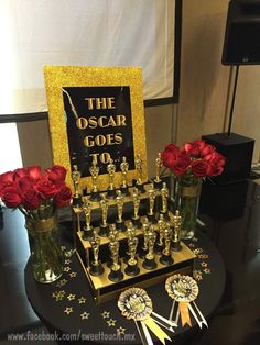 the oscars are on display with red roses in vases and an award plaque