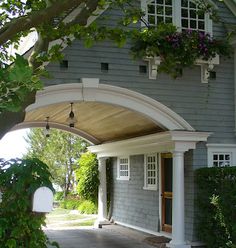 a gray house with white trim and flowers in the window boxes on the front porch