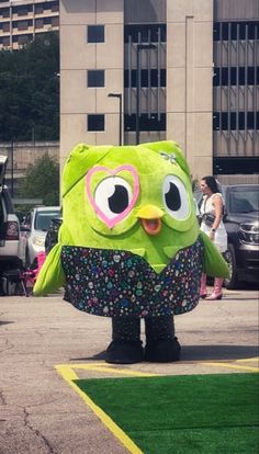 a large green stuffed animal standing on top of a parking lot