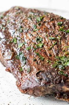 a piece of steak covered in sauce and herbs