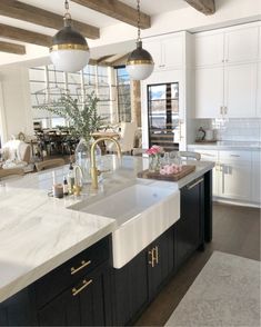 a large kitchen with marble counter tops and black cabinets, along with two hanging lights