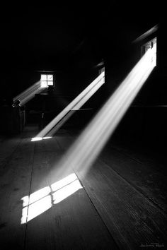 the sun is shining through two windows in an empty room with wooden floors and beams of light coming from them