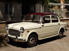 an old white car parked in front of a building