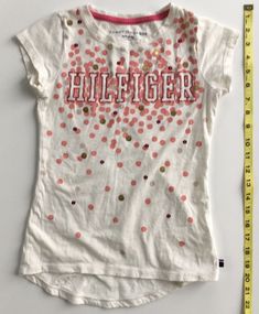 Tommy Hilfiger Girl's White T-Shirt Medium (8/10). The material is 100% cotton.  Condition is pre-owned.  The shirt was lightly used and is still in great condition.  There are no tears, stains, or rips.  See photos for the style and condition of the shirt. Girls White T Shirt, Tommy Hilfiger Girl, No Tears, The Shirt, White T Shirt, White T, White Tshirt, Baby Onesies, Tommy Hilfiger