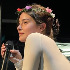 a woman wearing a flower crown holding a microphone