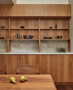 two pears sit on a wooden table in front of an open bookcase and shelves