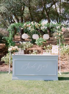 an outdoor ceremony area with flowers and greenery on the grass, decorated with hanging candles