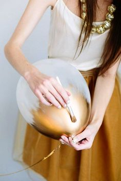 a woman in a white top is holding a gold and white frisbee with her hands