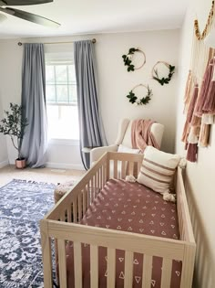 a baby's crib in the corner of a room with blue and pink curtains