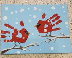 two red birds sitting on top of a tree branch covered in handprints and snow