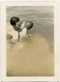 an old photo of a boy in the water with a life preserver on his back