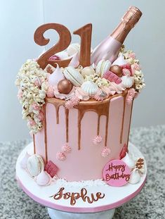 a pink birthday cake with champagne and flowers on the top is decorated with chocolate icing