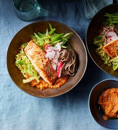 two bowls filled with different types of food on top of a blue cloth covered table