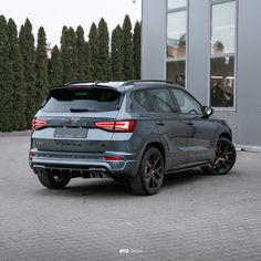 the rear end of a grey suv parked in front of a building