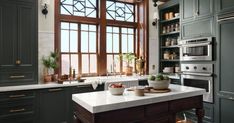 a kitchen with blue cabinets and an island in front of a window that has potted plants on it