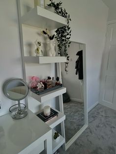 a room with a mirror, shelf and vases on top of the table in front of it