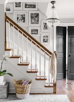 a white staircase with pictures on the wall and a basket under the bannister