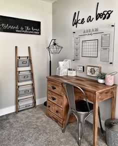 a wooden desk sitting in front of a white wall with writing on the wall above it