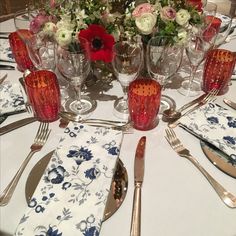 the table is set with silverware and flowers