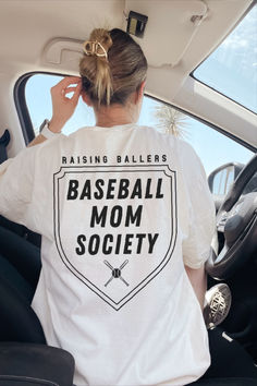 a woman sitting in the back seat of a car wearing a baseball mom t - shirt