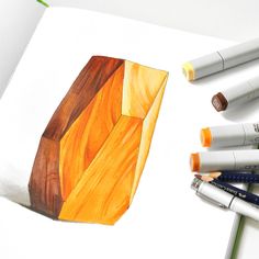 some markers and pens are laying on a piece of paper next to an orange vase