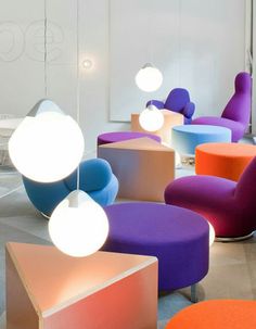 an assortment of colorful chairs and tables in a room with lights on the ceiling above them