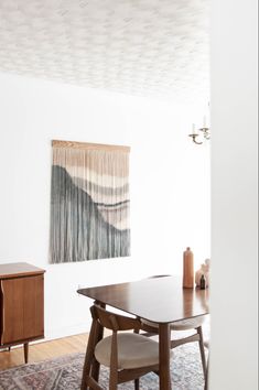 a dining room with a table and chairs in front of a painting on the wall