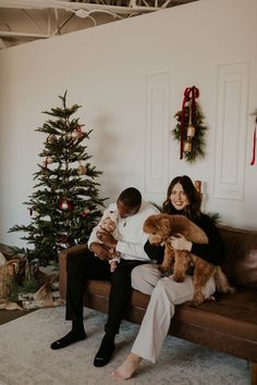 a woman sitting on top of a couch holding a stuffed animal next to a christmas tree