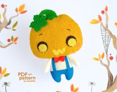 an orange doll hanging from a tree branch with leaves on it's head and wearing overalls