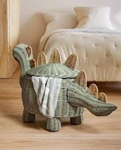 an elephant shaped basket sitting on top of a wooden floor next to a white bed