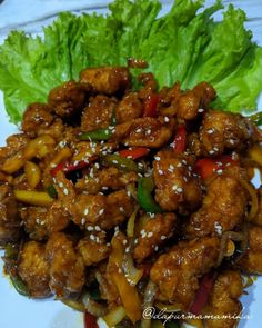 chicken with peppers and sesame seeds served on a white plate next to lettuce