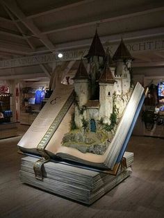 an open book shaped like a castle on top of a wooden floor in a museum