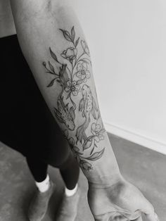 black and white photo of a woman's arm with flowers on the wrist tattoo