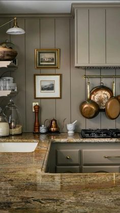 a kitchen counter with pots and pans hanging on the wall next to an oven