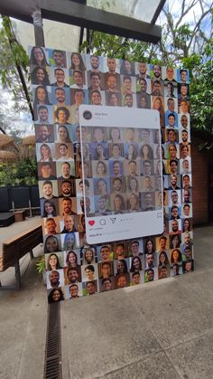 a group of people's faces on a wall with trees and benches in the background