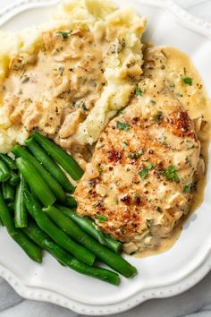 a white plate topped with meat, mashed potatoes and green beans