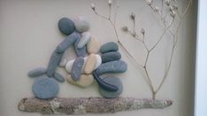 some rocks are arranged on a branch in front of a white wall with a plant