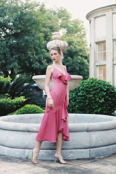 a woman in a pink dress standing next to a fountain