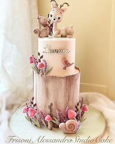 a three tiered cake decorated with deer and flowers on top of a tree stump