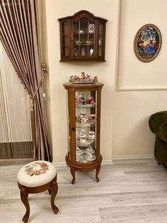 the corner of a living room with a chair and china cabinet